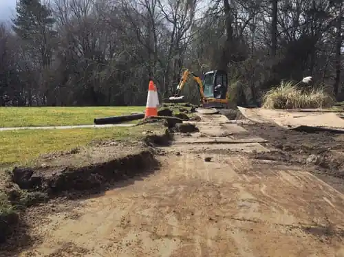 Mini excavator trenching an underground line across a lawn